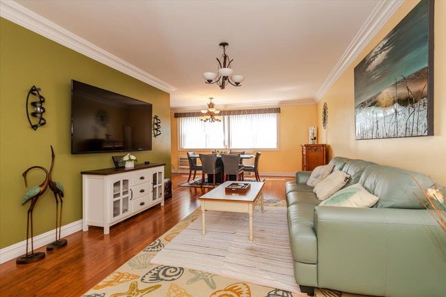 Living room featuring a chandelier, ornamental molding, and wood finished floors | Image 5