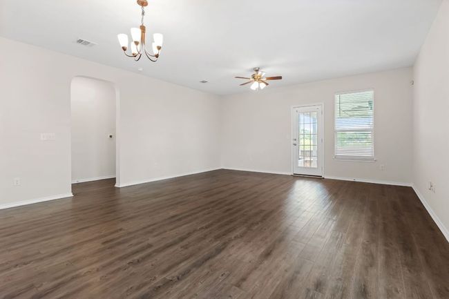 Empty room with arched walkways, ceiling fan, dark wood-style floors, and a chandelier | Image 28