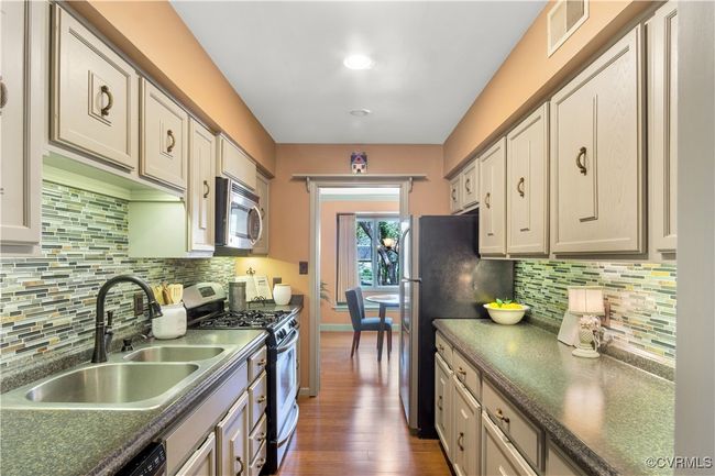 Kitchen with dark wood-style floors, dark countertops, visible vents, stainless steel appliances, and a sink | Image 6