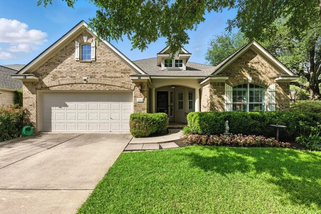 Traditional home featuring brick siding, a garage, driveway, a front yard, and a shingled roof | Image 5