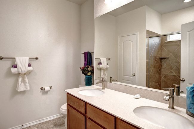 Bathroom featuring double vanity and tiled shower | Image 24