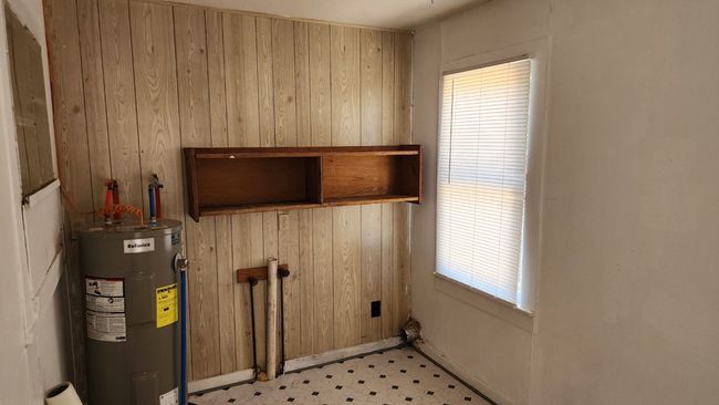 Laundry area featuring light floors, electric water heater, and wooden walls | Image 12
