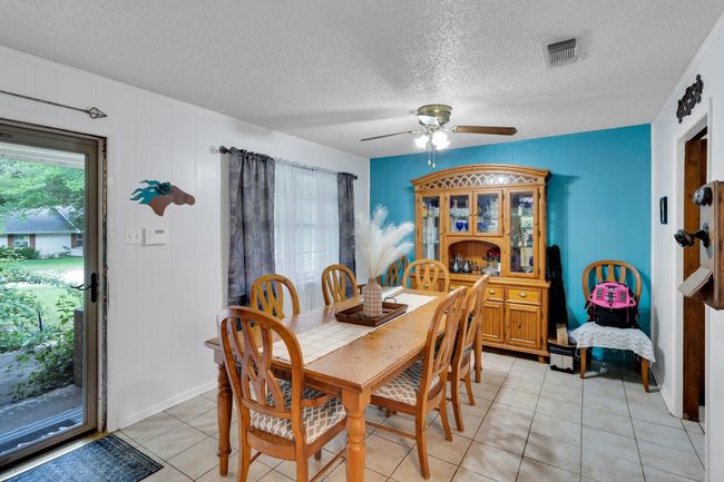 Dining room with light tile patterned flooring, a ceiling fan, and a textured ceiling | Image 4