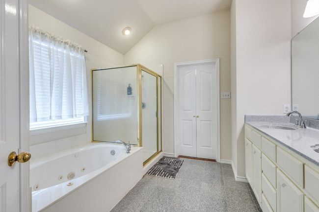 Full bathroom featuring a shower stall, a whirlpool tub, vaulted ceiling, and vanity | Image 17