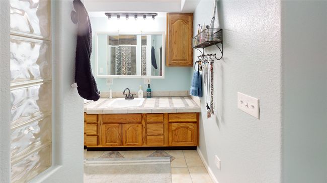 Bathroom featuring a textured wall, a shower stall, vanity, and light tile patterned floors | Image 25