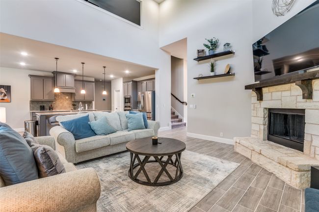 Living room featuring wood finish floors, a fireplace, a high ceiling, recessed lighting, and stairs | Image 8