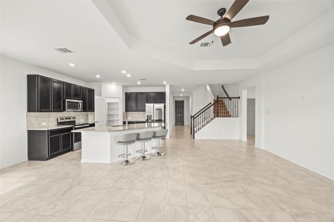 Kitchen with stainless steel appliances, dark cabinets, backsplash, a breakfast bar, and recessed lighting | Image 9