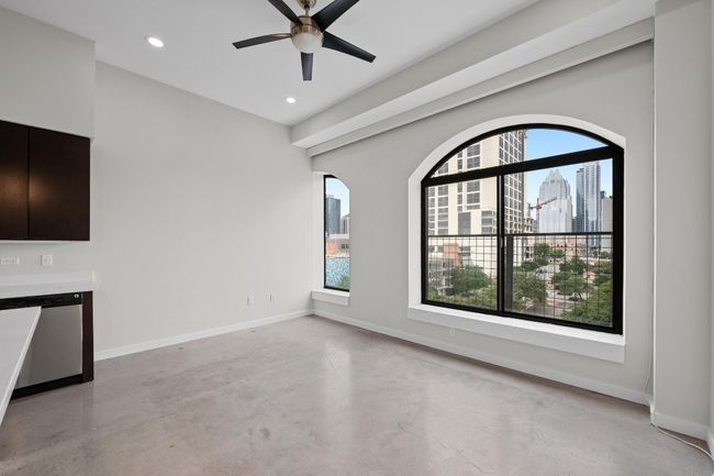 Unfurnished living room with ceiling fan, concrete floors, recessed lighting, baseboards, and a city view | Image 10