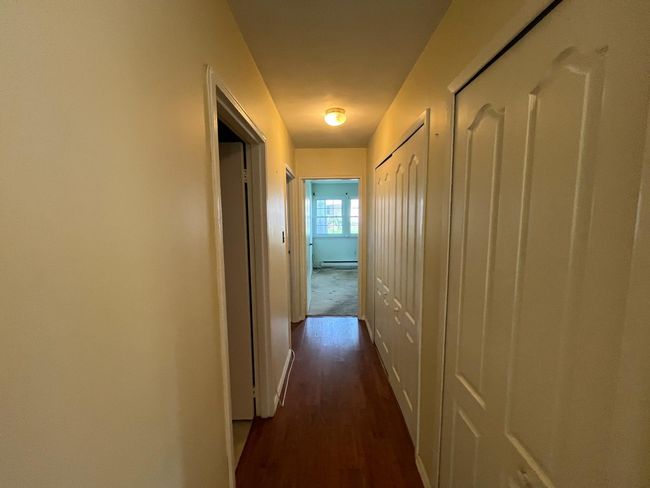 Corridor featuring dark wood-type flooring, a baseboard radiator, and baseboards | Image 6