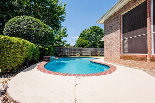 View of swimming pool with a patio area and a fenced backyard | Image 13
