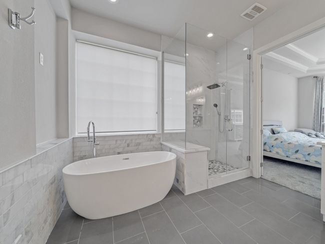Full bathroom with tile walls, a stall shower, a freestanding tub, ensuite bath, and tile patterned flooring | Image 14