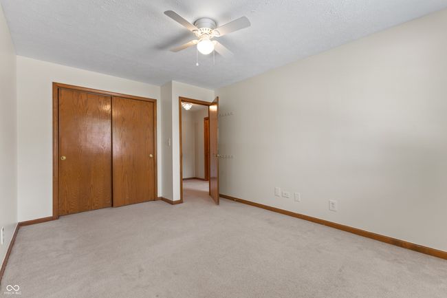 unfurnished bedroom with light carpet, baseboards, a closet, a ceiling fan, and a textured ceiling | Image 25