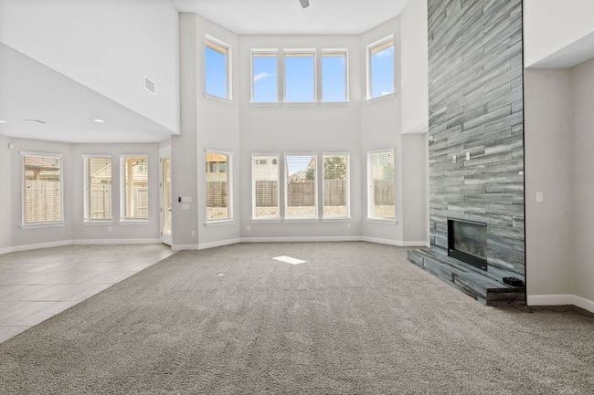 Unfurnished living room featuring a wealth of natural light, baseboards, and a high ceiling | Image 12