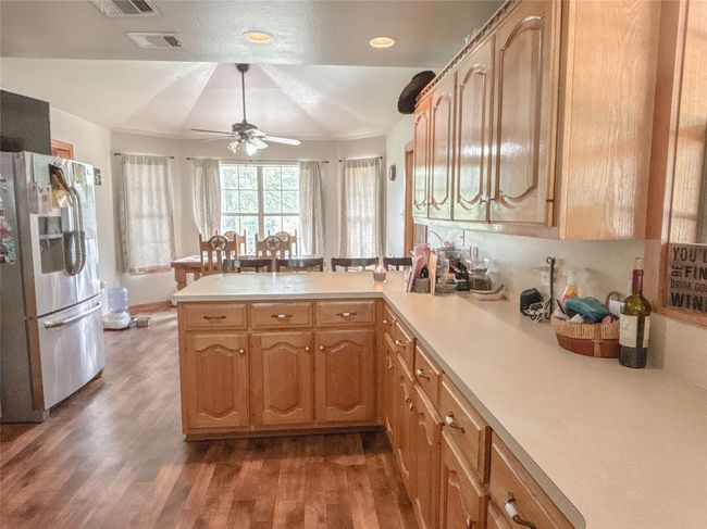 Kitchen with stainless steel fridge, a peninsula, wood finished floors, and light countertops | Image 14
