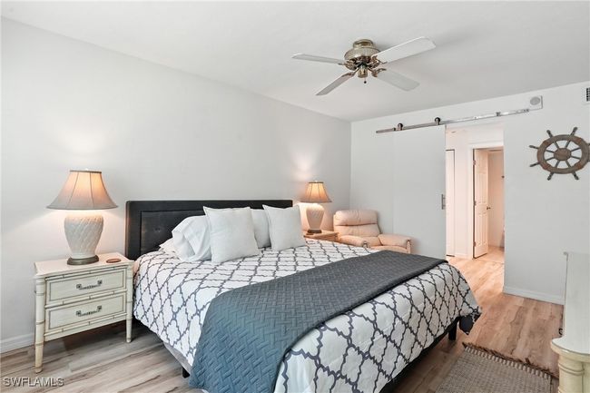 Bedroom with a barn door, wood finished floors, and a ceiling fan | Image 25