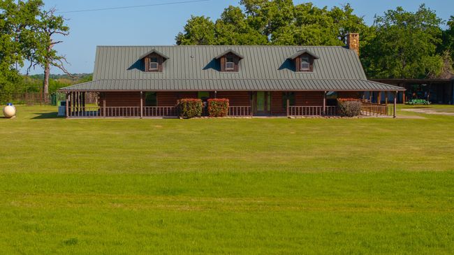 View of front of home with a chimney, covered porch, a front yard, and metal roof | Image 6