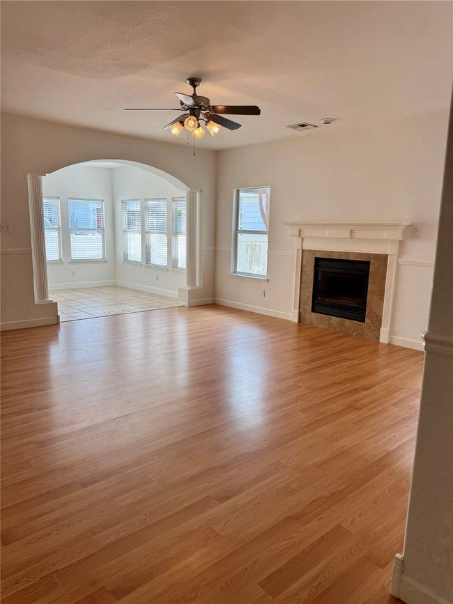 Unfurnished living room with light wood-style flooring, ceiling fan, a tiled fireplace, and baseboards | Image 5