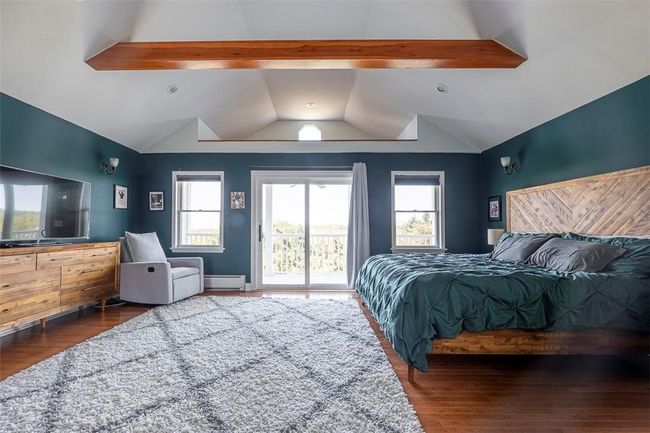 Bedroom featuring a baseboard radiator, lofted ceiling with beams, dark hardwood / wood-style flooring, and access to outside | Image 21