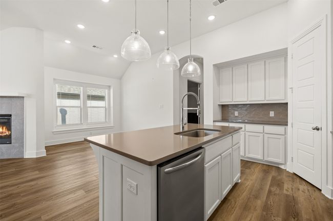 Kitchen with tasteful backsplash, a sink, dishwasher, a kitchen island with sink, and wood finished floors | Image 12
