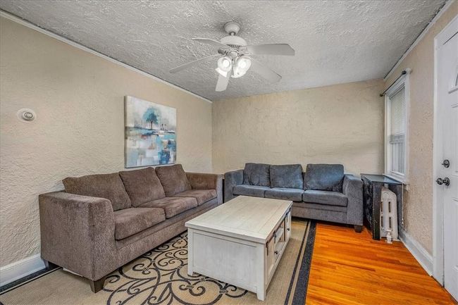 UNIT# 70 Living room with a textured ceiling, light wood-type flooring, and ceiling fan | Image 24