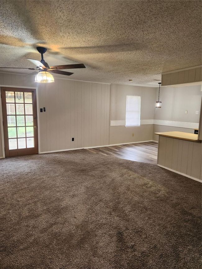 Unfurnished living room with carpet floors, ceiling fan, and a textured ceiling | Image 5