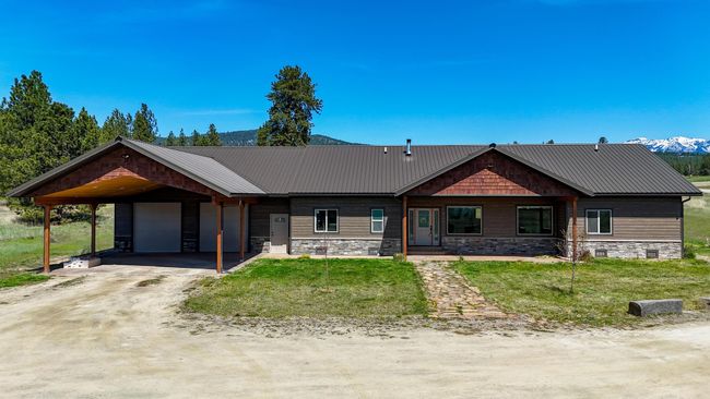 View of front facade with driveway, a carport, metal roof, an attached garage, and a front lawn | Image 39