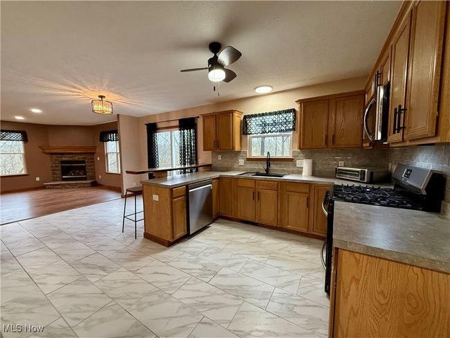 Kitchen with appliances with stainless steel finishes, a sink, a peninsula, open floor plan, and light marble finish flooring | Image 8