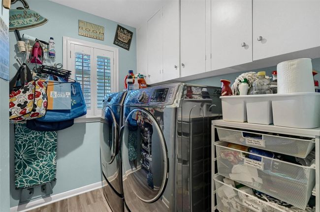 Laundry room featuring independent washer and dryer, cabinet space, wood finished floors, and baseboards | Image 32
