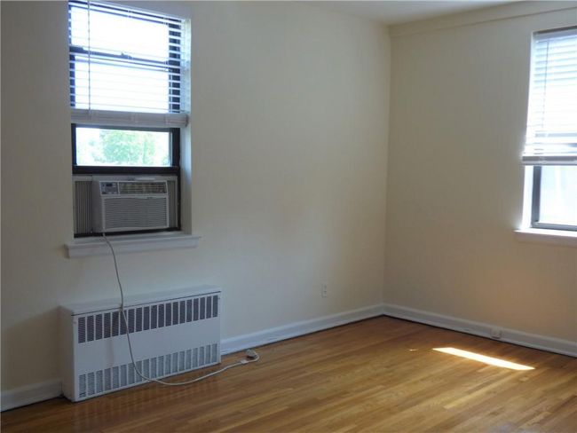 Bedroom featuring a wealth of natural light, baseboards, radiator, and wood finished floors | Image 15