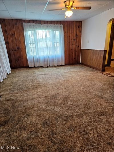 Empty room with carpet flooring, ceiling fan, and a paneled ceiling | Image 2