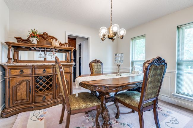 Dining room with a chandelier, plenty of natural light, light wood finished floors, and a wainscoted wall | Image 8