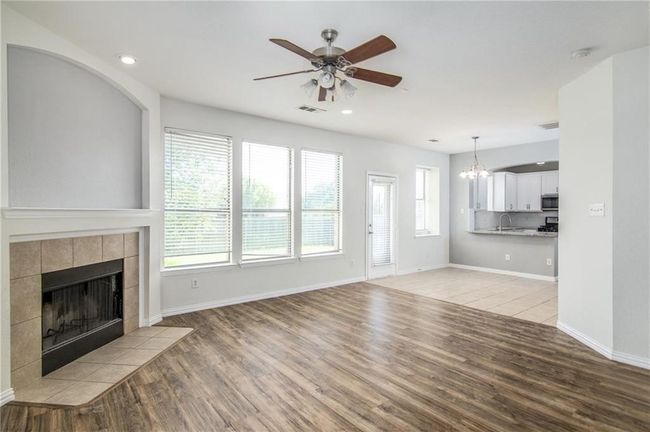 Unfurnished living room with ceiling fan, light wood-style floors, a tile fireplace, a chandelier, and recessed lighting | Image 9