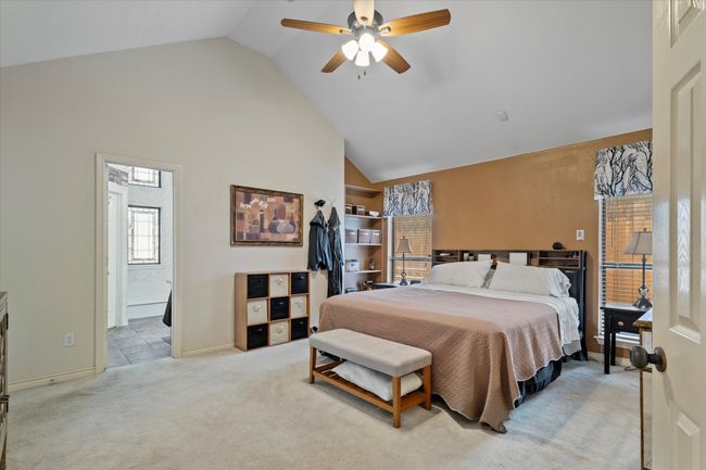 Carpeted bedroom featuring high vaulted ceiling, ensuite bath, baseboards, and a ceiling fan | Image 21