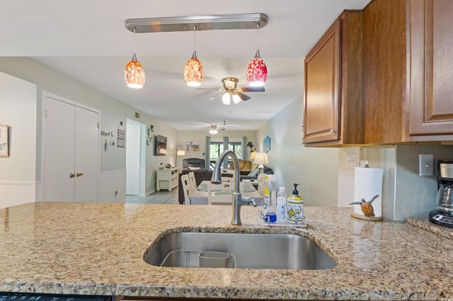 Kitchen with brown cabinets, a ceiling fan, open floor plan, and a sink | Image 5