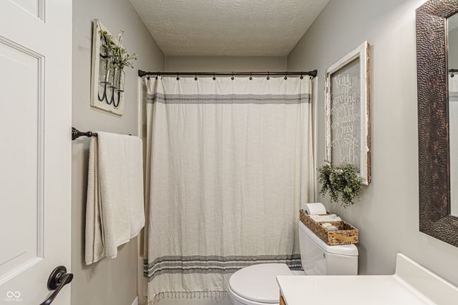 bathroom with a textured ceiling, toilet, vanity, and a shower with curtain | Image 18