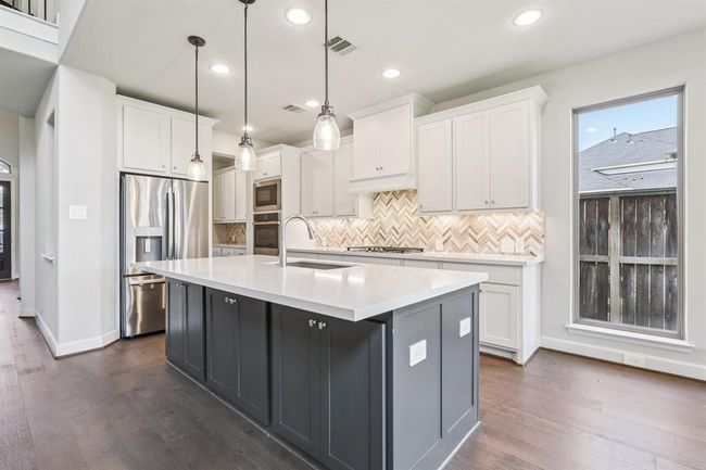Beautiful granite countertops and a large center island offer ample prep space, while built-in storage keeps the kitchen both elegant and efficient. | Image 12