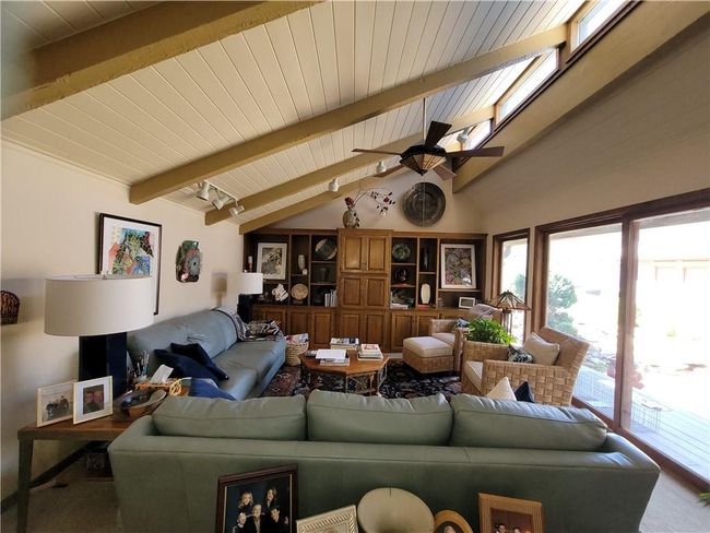 Living area with lofted ceiling with beams, wooden ceiling, and a ceiling fan | Image 18