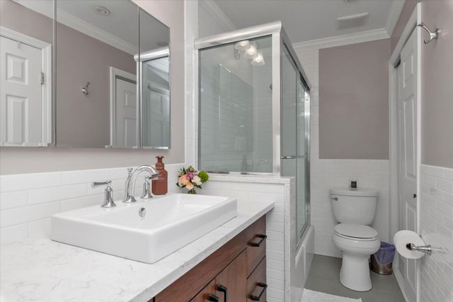 Bathroom with tile walls, visible vents, crown molding, toilet, and vanity | Image 9