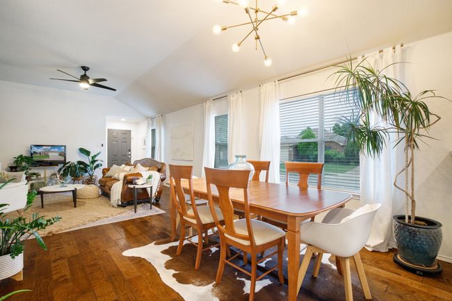 Dining area with hardwood / wood-style floors, vaulted ceiling, a ceiling fan, and a chandelier | Image 6