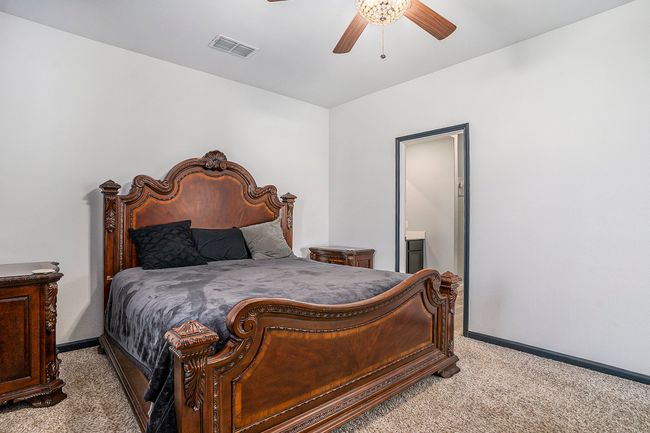 Primary Bedroom featuring light colored carpet, baseboards, ensuite bath, and ceiling fan. | Image 14