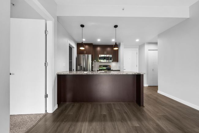 Kitchen with appliances with stainless steel finishes, baseboards, dark wood-style flooring, a sink, and a peninsula | Image 25
