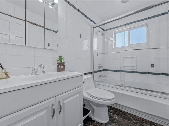 Bathroom with vanity, tile walls, toilet, granite finish floor, and enclosed tub / shower combo | Image 20