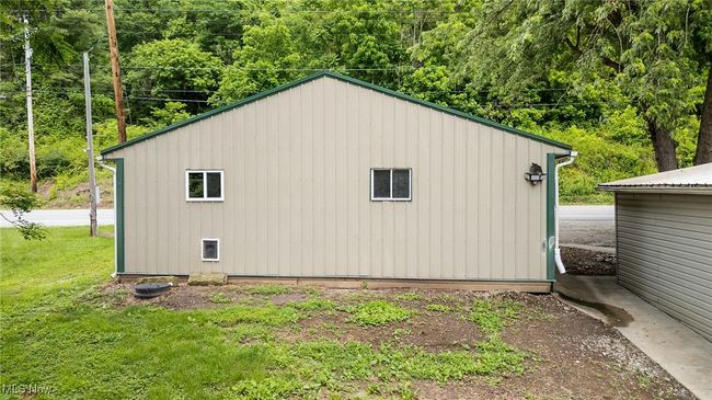 View of side of garage featuring a wooded view and a lawn | Image 5