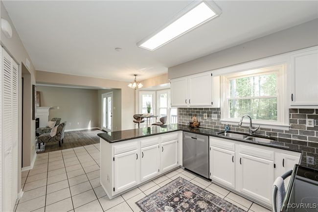 Kitchen with a peninsula, a sink, electric range oven, dishwasher, and light tile patterned floors | Image 11