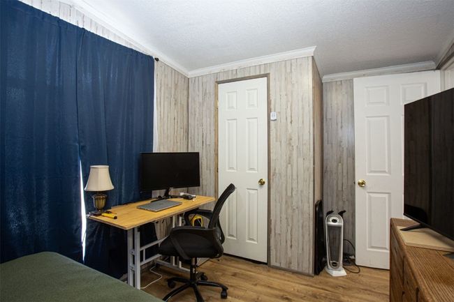 Office with a textured ceiling, crown molding, hardwood / wood-style floors, and wood walls | Image 15