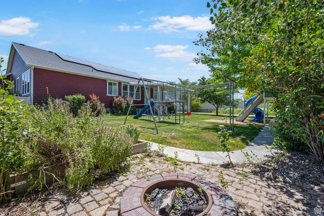 View of green lawn with a playground, a fire pit, and a vegetable garden | Image 36