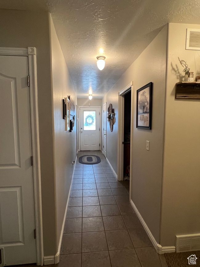 Entryway featuring baseboards, visible vents, dark tile patterned flooring, and a textured ceiling | Image 29