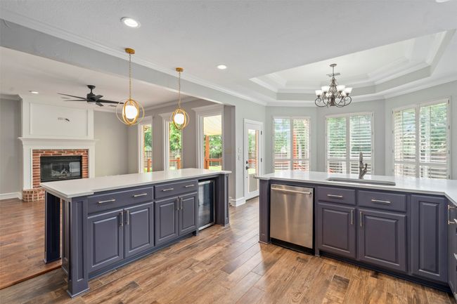 Kitchen featuring dishwasher, a sink, beverage cooler, ornamental molding, and plenty of natural light | Image 17