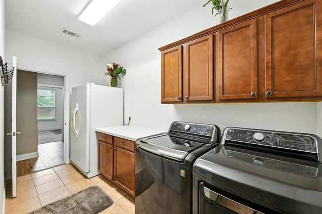 Laundry area with cabinet space, separate washer and dryer, and light tile patterned flooring | Image 36