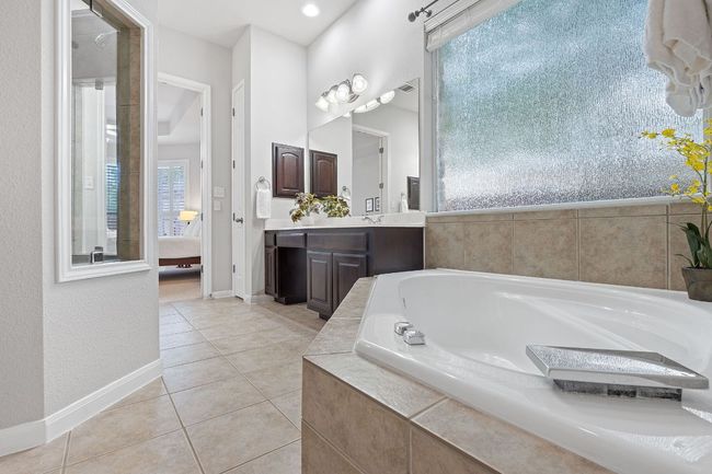 Bathroom with a bath, vanity, tile patterned flooring, ensuite bathroom, and baseboards | Image 12